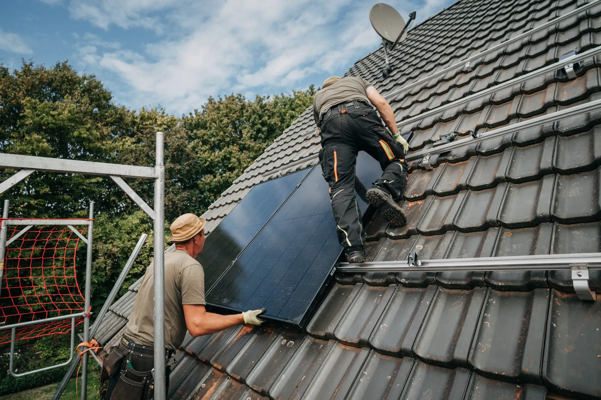 Zwei Monteure setzen ein Solarmodul auf das Dach