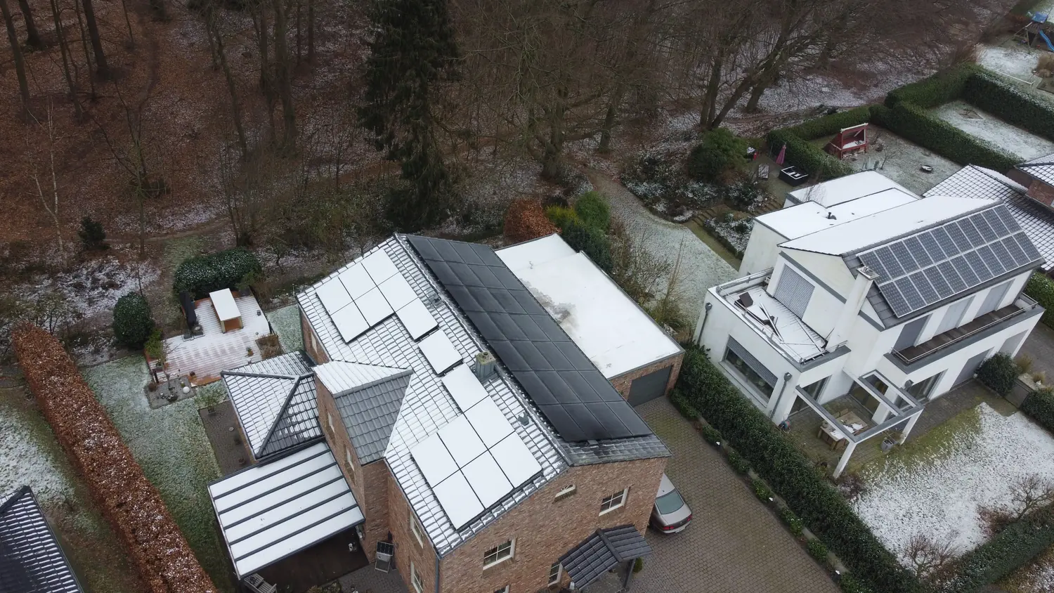 Photovoltaikanlage auf Ziegel- und Flachdach eines Wohnhauses im Winter, Luftaufnahme