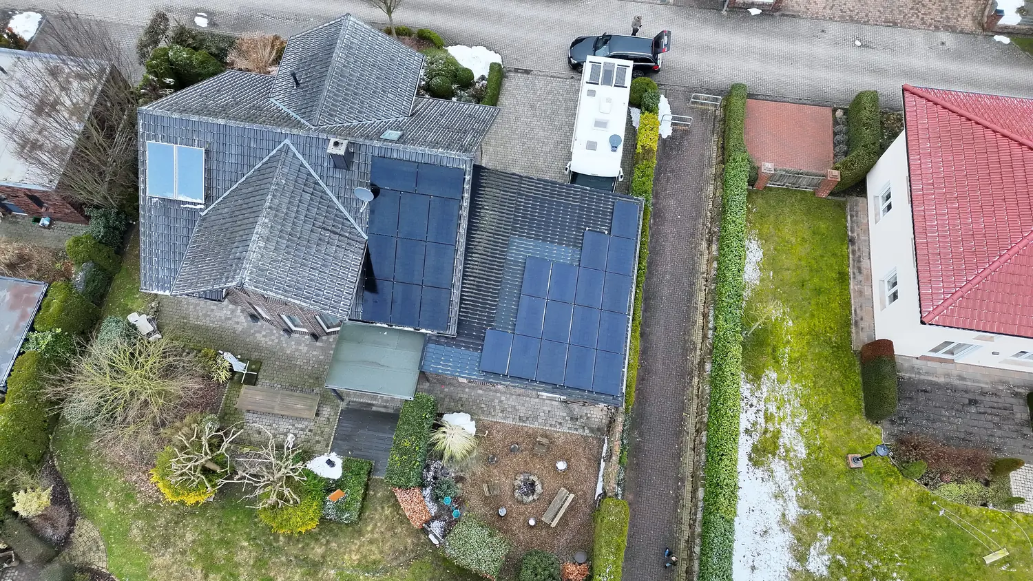 Photovoltaikmodule auf zwei Dachflächen eines Wohnhauses im Winter, Luftaufnahme