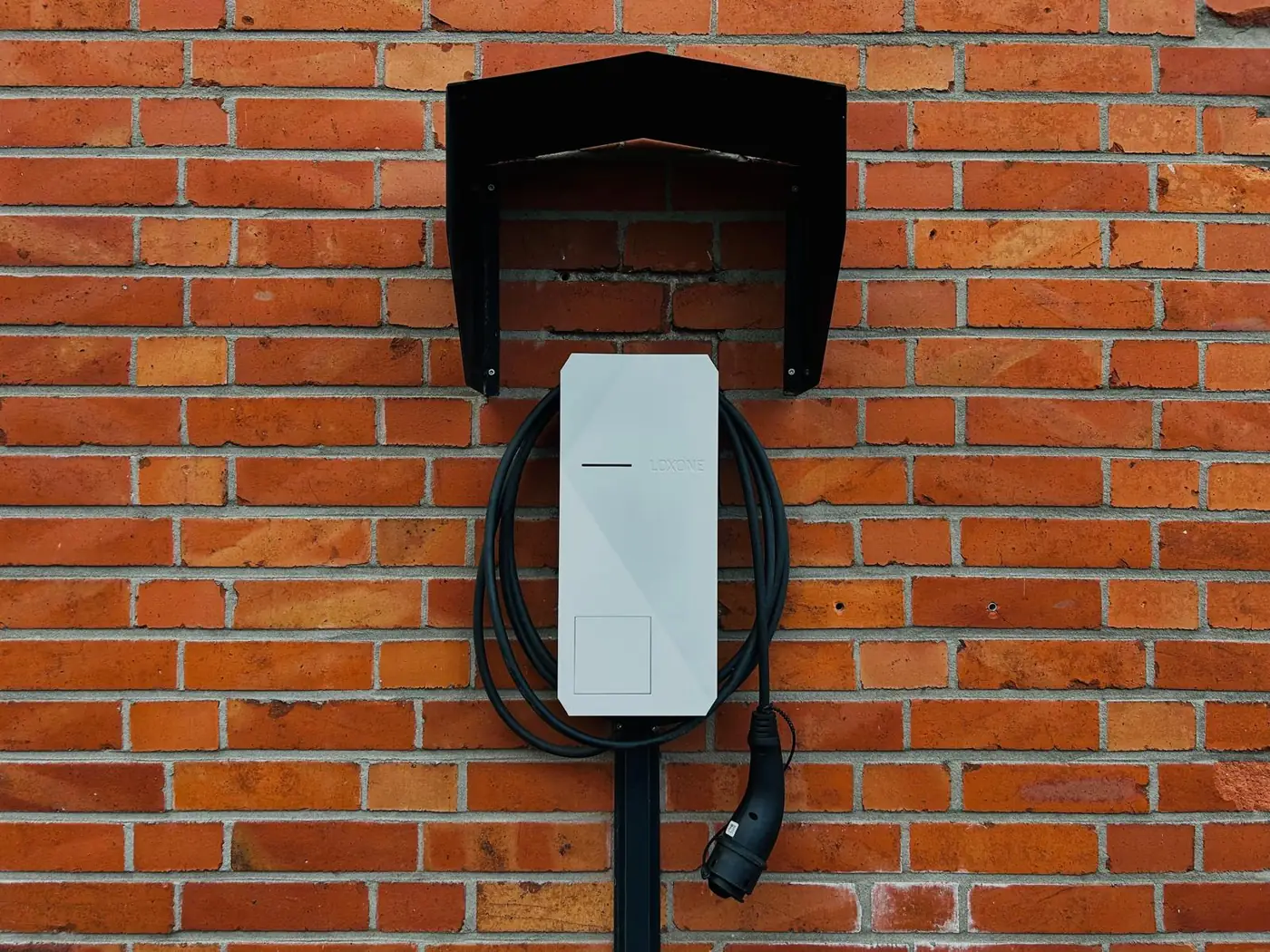Von Heye-Enneking installierte Wallbox mit aufgewickeltem Ladekabel und Typ-2-Stecker unter einem Wetterschutzdach